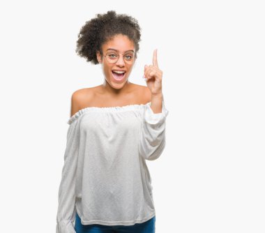 Başarılı fikirle izole arka plan işaret parmağı üzerinde gözlük takan genç afro Amerikalı kadın. Çıktıktan ve mutlu. Bir numara.