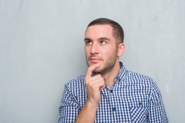 Gri grunge duvar ciddi bir yüz düşünme hakkında soru, çok karışık fikir genç beyaz adam