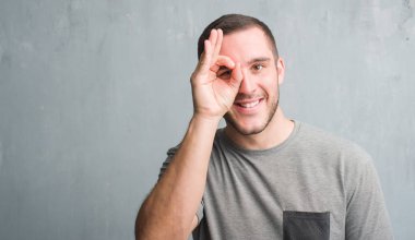 Mutlu yüz el parmaklarının arasından seyir göz üzerinde ok işaretiyle yapıyor gülümseyen ile gri grunge duvarın üzerinden beyaz delikanlı