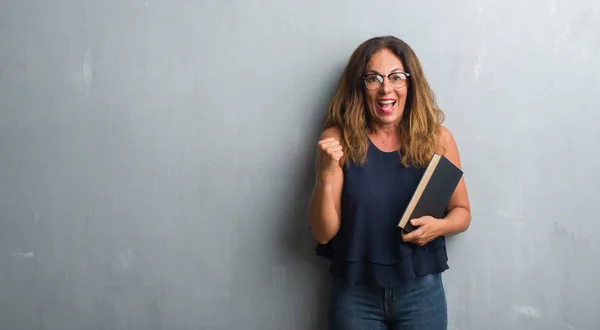 Mulher Hispânica Meia Idade Sobre Parede Grunge Cinza Segurando Livro — Fotografia de Stock