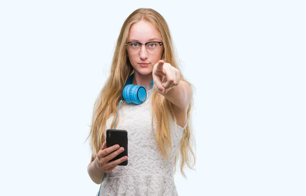 Blonde Teenager Woman Holding Smartphone Wearing Headphones Pointing Finger Camera — Stock Photo, Image