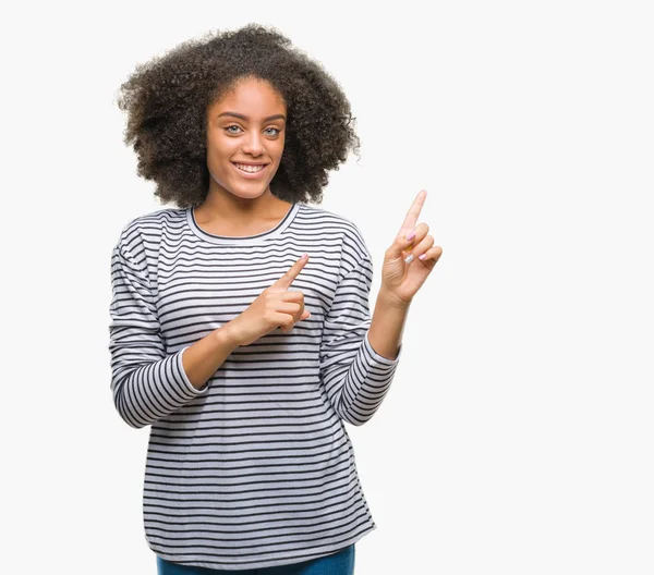 Genç afro Amerikalı kadın gülümseyerek ve iki elleri ve parmakları ile tarafına işaret kamera bakarak izole arka plan üzerinde.