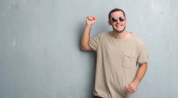 Joven Hombre Caucásico Sobre Pared Gris Grunge Usando Gafas Sol —  Fotos de Stock