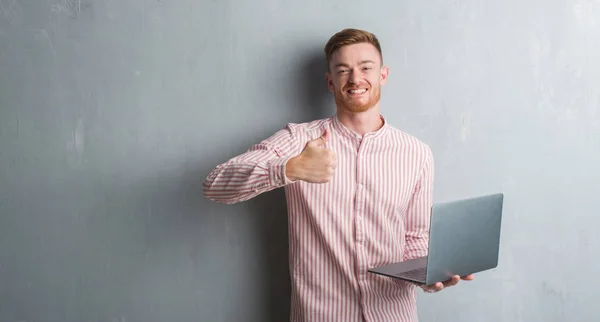 Homem Ruivo Jovem Sobre Parede Grunge Cinza Segurando Usando Laptop — Fotografia de Stock