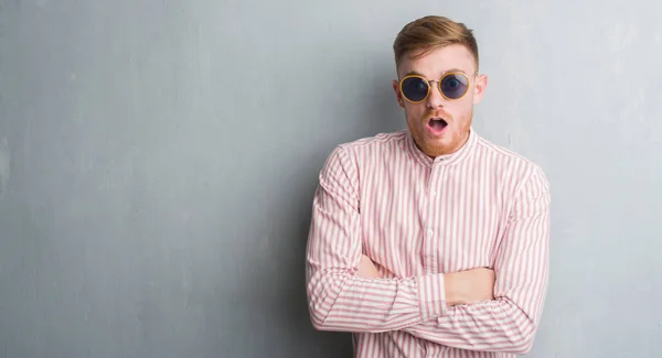 Young Redhead Man Grey Grunge Wall Wearing Retro Sunglasses Scared — Stock Photo, Image