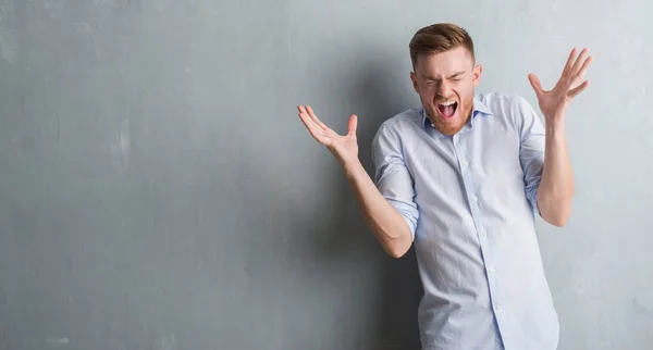 Joven Hombre Negocios Pelirroja Sobre Pared Grunge Gris Celebrando Loco — Foto de Stock