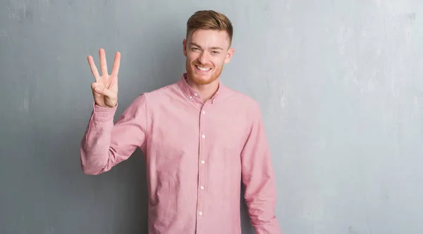 Young Redhead Man Grey Grunge Wall Wearing Pink Shirt Showing — Stock Photo, Image