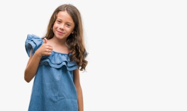 Brunette hispanic girl wearing denim dress happy with big smile doing ok sign, thumb up with fingers, excellent sign clipart