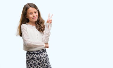 Esmer Latin kız mutlu yüz zafer işareti yaparken kameraya göz kırpıyor ile gülümseyen. İki numaralı.