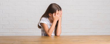 Üzgün ifade yüz eller ile ağlayarak süre kapsayan ile evde masaya oturan genç İspanyol çocuk. Depresyon kavramı.
