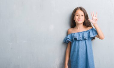 Genç İspanyol çocuğun gösterilen ve parmakları ile işaret grunge gri duvarın üzerinden dört kendinden emin ve mutlu gülümseyerek iken numara.
