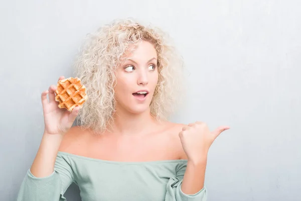 Joven Rubia Sobre Fondo Gris Grunge Comiendo Gofres Belgas Señalando —  Fotos de Stock