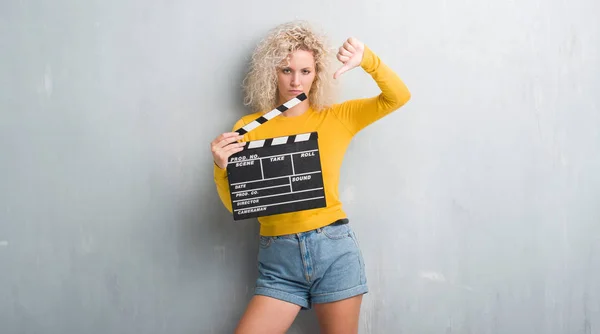 Young Blonde Woman Grunge Grey Wall Holding Calpboard Movie Angry — Stock Photo, Image