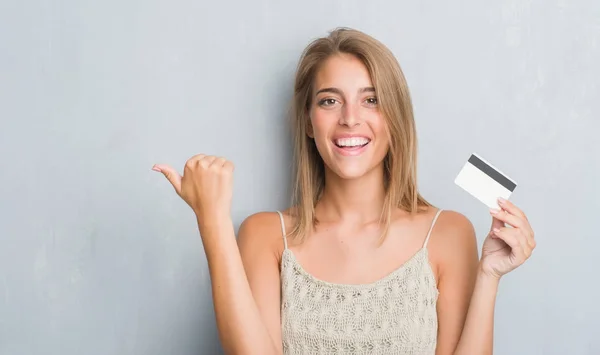 Beautiful Young Woman Grunge Grey Wall Holding Credit Card Pointing — Stock Photo, Image