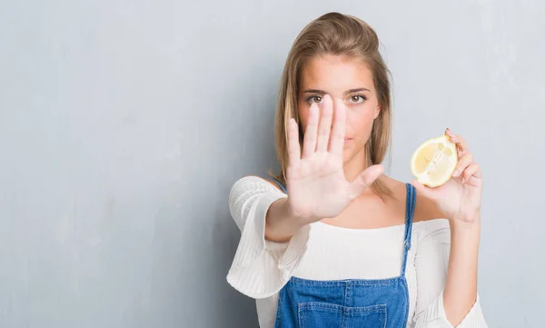 Hermosa Mujer Joven Sobre Pared Gris Grunge Sosteniendo Limón Con —  Fotos de Stock