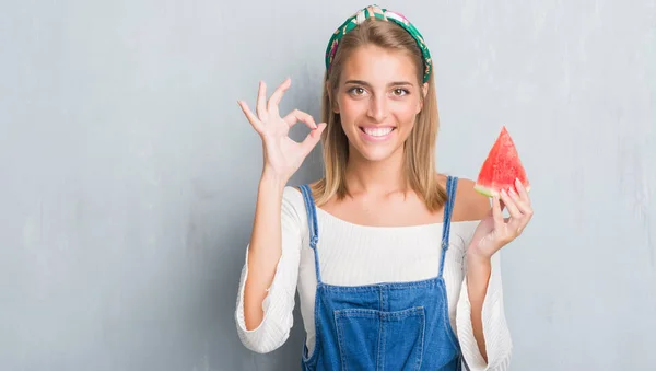 優秀なシンボルの指で サインをしてスイカを食べるグランジ灰色の壁に美しい若い女性 — ストック写真