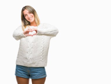 Kalp simgesi ve elleriyle şekil gösterilen aşık gülümseyen izole arka plan üzerinde kış kazak giyen genç güzel kadın. Romantik kavramı.