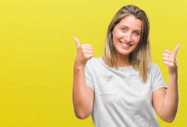 Genç güzel kadın el ile pozitif jest yapıyor izole arka plan başarı işareti yüzünden başparmak gülümseyen ve mutlu. Neşeli bir ifadeyle, kazanan jest kameraya bakıyor.