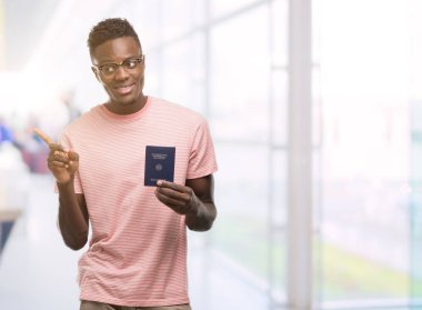 Alman pasaportu çok mutlu el ve parmak ile tarafına işaret tutan genç Afro-Amerikan adam