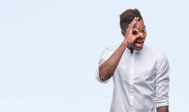 Genç Afro-Amerikan adam gülümsüyor, parmakları ile mutlu yüz üzerinden seyir göz el ile ok jest yapıyor izole arka plan üzerinde.