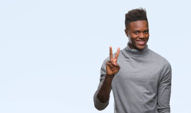 Gösterilen ve parmakları ile işaret izole arka plan üzerinde genç Afro-Amerikan adam ikincisi ise kendinden emin ve mutlu gülümseyerek.