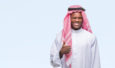 Geleneksel keffiyeh hareketi el ile mutlu yaşasın yapıyor izole arka plan üzerinde giyen genç Arapça Afrika adam. Kameraya bakarak başarı gösteren ile ifade onaylama.