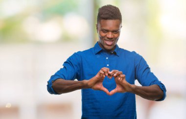Afrikalı-Amerikalı genç aşık kalp simgesi ve elleriyle şekil gösteren gülümseyen izole arka plan üzerinde. Romantik kavramı.