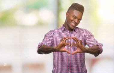 Afrikalı-Amerikalı genç aşık kalp simgesi ve elleriyle şekil gösteren gülümseyen izole arka plan üzerinde. Romantik kavramı.