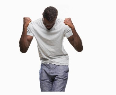 Gülümseyen ve başarı için çığlık genç Afro-Amerikan adam izole arka plan çok mutlu ve heyecanlı kaldırdı, silah ile kazanan jest yapıyor. Kutlama kavramı.