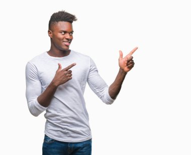 Gülümseyen ve iki elleri ve parmakları ile tarafına işaret kamera bakarak izole arka plan üzerinde genç Afro-Amerikan adam.