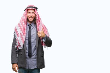 Genç yakışıklı Arap adam uzun saçlı hareketi el ile mutlu yaşasın yapıyor izole arka plan üzerinde keffiyeh giyiyor. Kameraya bakarak başarı gösteren ile ifade onaylama.