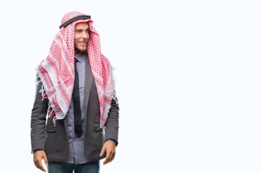 Genç yakışıklı Arap adam uzun saçlı uzak tarafına yüzünde, doğal ifade gülümseme ile seyir izole arka plan üzerinde keffiyeh giyiyor. Kendine güvenen gülüyor.