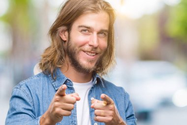 Yakışıklı delikanlı için fotoğraf makinesi ile mutlu ve komik yüz parmakları işaret izole arka plan üzerinde uzun saçlı. İyi enerji ve vibes.