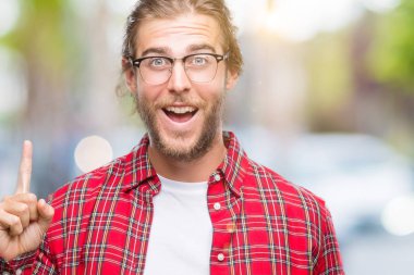 Yakışıklı delikanlı ile başarılı fikir izole arka plan işaret parmağı üzerinde gözlük takan uzun saçlı. Çıktıktan ve mutlu. Bir numara.