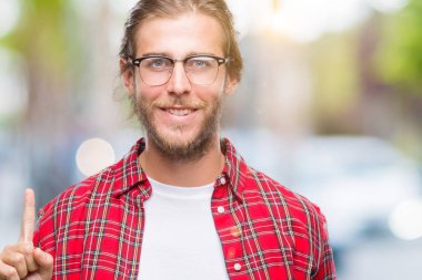 Genç yakışıklı adam uzun saçlı gözlüklü üzerinde gösterilen ve kendinden emin ve mutlu gülümseyen bir parmak ile işaret eden oktan yukarı izole arka plan.
