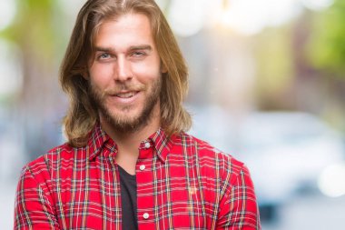 Kameraya bakarak çapraz silah ile gülümseyen izole arka plan mutlu yüzüne uzun saçlı Genç yakışıklı adam. Olumlu bir kişi.