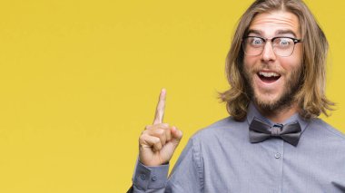 Genç yakışıklı adam uzun saçlı başarılı fikirle izole arka plan işaret parmağı üzerinde papyon giyiyor. Çıktıktan ve mutlu. Bir numara.