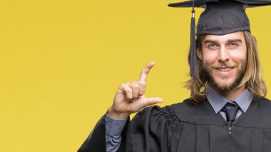 Genç yakışıklı adam uzun saçlı izole arka plan gülümseyen ve süre seyir ve kamera boyutu işaret parmaklarıyla yapıyor el ile kendinden emin eller üzerinde mezun oldu. Ölçü kavramı.