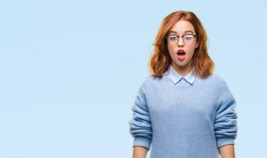 İzole arka plan kış kazak korkuyor ve şok sürpriz ifade, korku ve heyecan yüz ile giyen genç güzel kadın.