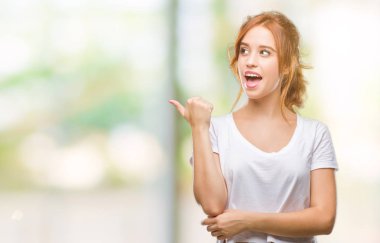 Seyir ve başparmak yanında yukarıyı mutlu yüz ile gülümseyen izole arka plan üzerinde genç güzel kadın.