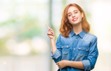 Kameraya bakarak yan el ve parmak ile işaret izole arka yüzünde kocaman bir gülümseme ile genç güzel kadın.