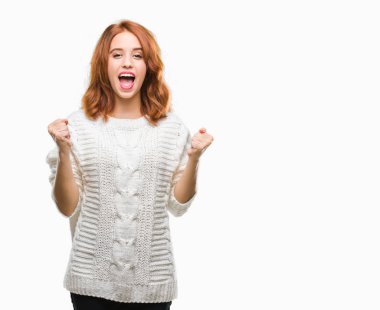 İzole arka plan kutlama kış kazak giyen genç güzel kadın şaşırttı ve başarı için kaldırdı kollarını açarak hayret ve gözleri açık. Kazanan kavramı.