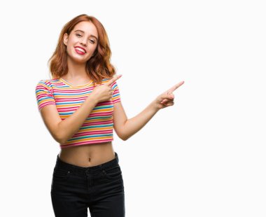 Gülümseyen ve iki elleri ve parmakları ile tarafına işaret kamera bakarak izole arka plan üzerinde genç güzel kadın.