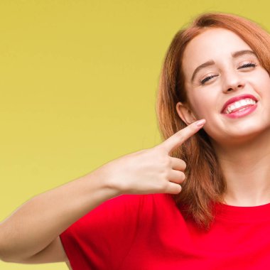 Genç güzel kadın kendinden emin gösterilen ve işaret parmakları diş ve ağız ile gülümseyen izole arka plan yüzünden. Sağlık kavramı.