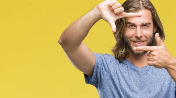 Young handsome man with long hair over isolated background smiling making frame with hands and fingers with happy face. Creativity and photography concept.