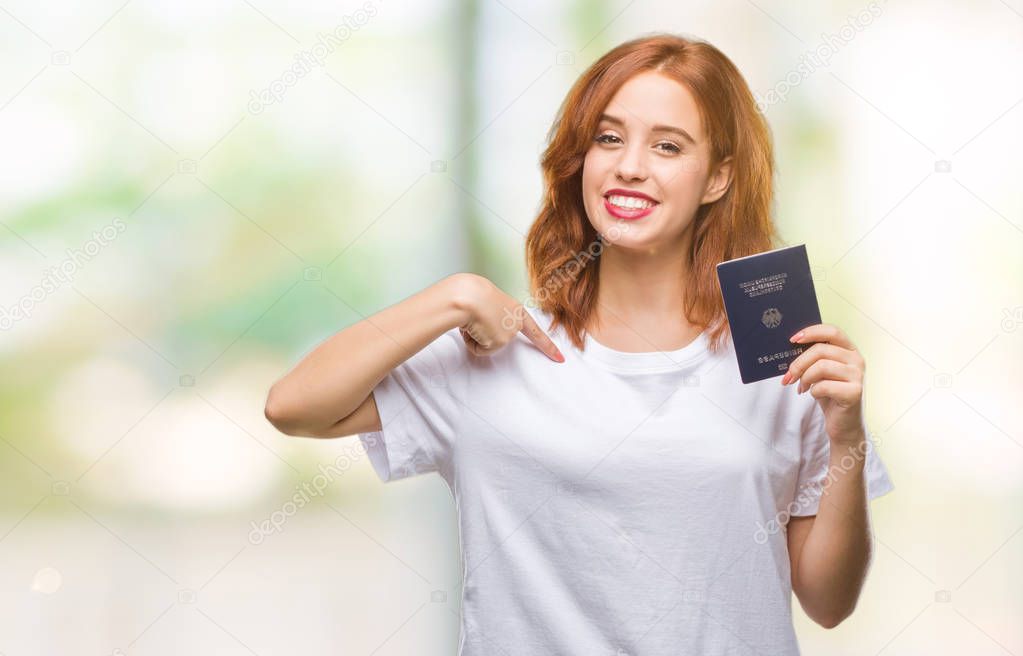Young beautiful woman holding passport of germany over isolated background with surprise face pointing finger to himself