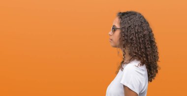 Yan, doğal yüz emin gülümseme ile pozuyla profil rahatla aramaya güneş gözlüğü takmış genç İspanyol kadın.