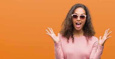 Güzel genç İspanyol kadın deli kutluyor ve silah ile başarı için heyecanlı çığlık kaldırdı ve açık gözleri hayret güneş gözlüğü takıyor. Kazanan kavramı