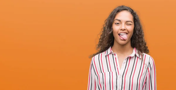 Beautiful young hispanic woman sticking tongue out happy with funny expression. Emotion concept.