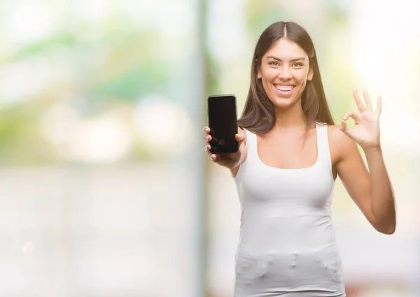 Joven Hispano Hermoso Mostrando Teléfono Inteligente Haciendo Signo Con Los — Foto de Stock